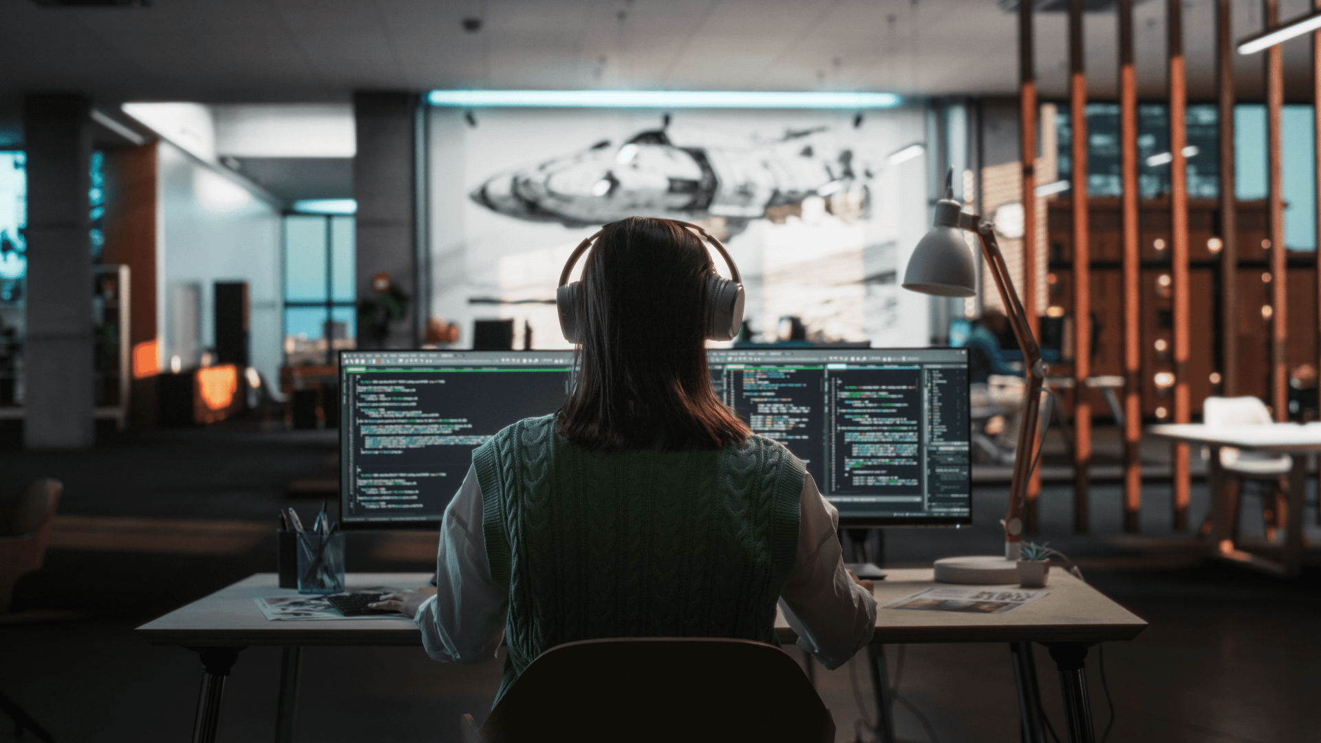 woman sitting at desk wearing headphones working on a computer